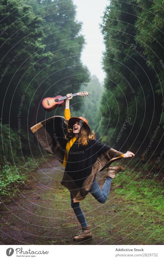Springende Frau mit Ukulele im Wald Fröhlichkeit Freiheit springen Nebel Reisender Ausdruck Aufregung Bewegung romantisch Energie Ausflug kalt über der Erde
