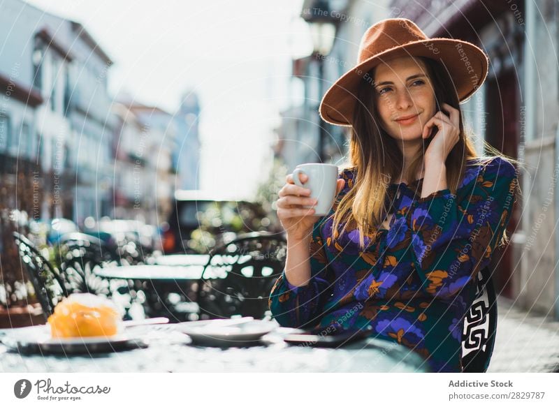 Frau mit Cup und Smartphone im Außencafé hübsch Stil Straße Hut Kaffee Tasse Café Außenaufnahme Mode schön Jugendliche Porträt attraktiv Großstadt Lifestyle