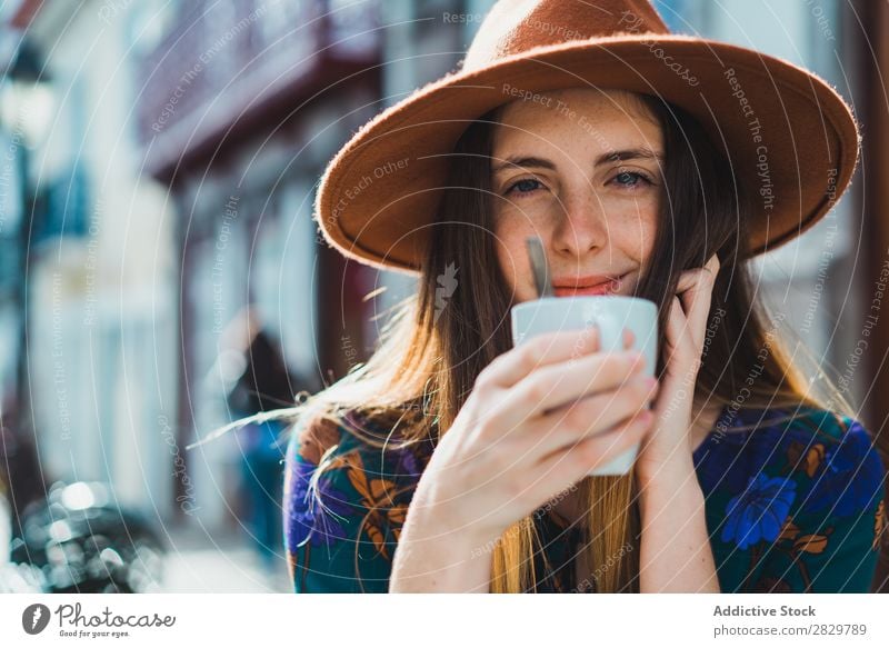 Lächelnde Frau mit Tasse im Außencafé hübsch Stil Straße Hut Kaffee Café Außenaufnahme Mode schön Jugendliche Porträt attraktiv Großstadt Lifestyle Model
