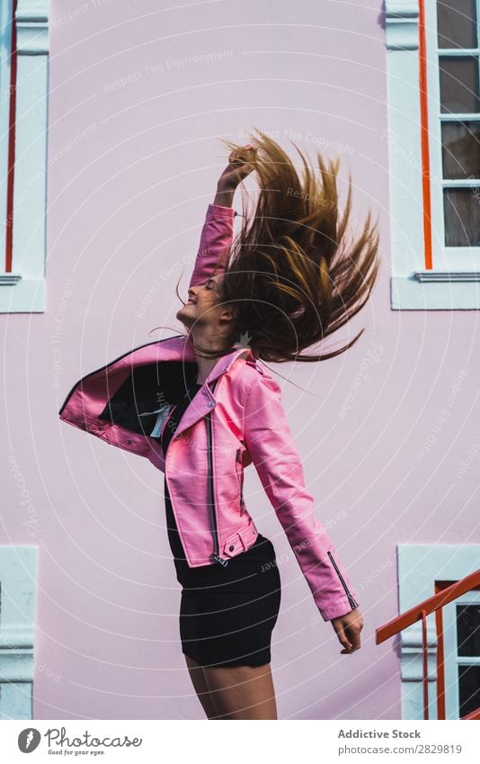 Glückliche Frau mit fliegenden Haaren hübsch Stil Behaarung springen Straße Außenaufnahme Mode schön Jugendliche Porträt attraktiv Großstadt Lifestyle Model