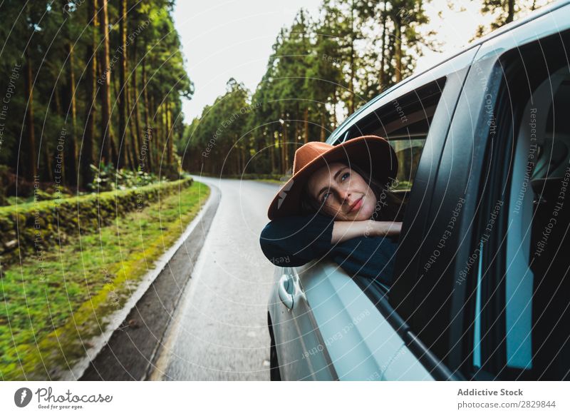 Frau, die im Wald aus dem Auto hängt. PKW Fenster herumhängen grün träumen Hut hübsch Straße Asphalt Natur Umwelt natürlich Jahreszeiten Pflanze Blatt Licht