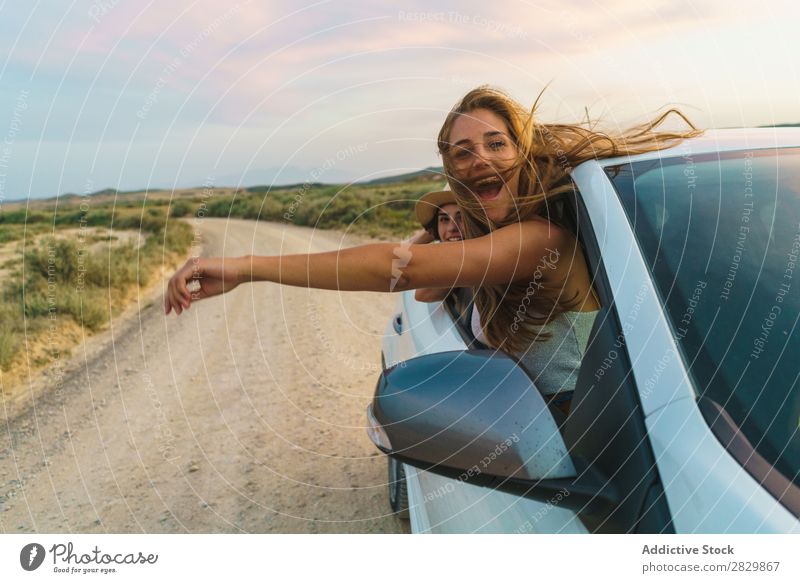 Frauen, die aus dem Auto hängen. PKW Natur Blick in die Kamera hinaushängend Fenster Feld Freude Lifestyle Jugendliche Glück Ferien & Urlaub & Reisen Fahrzeug