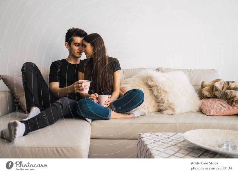 Paar sitzt auf der Couch heimwärts Zusammensein sitzen umarmend Sofa Liege gemütlich Mensch Glück Liebe Haus Mann Frau Lifestyle 2 Jugendliche Erwachsene