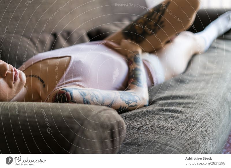 Junge hübsche Frau, die auf dem Sofa liegt. Mensch Tattoo lügen Unterwäsche schön Körper Beautyfotografie Jugendliche Erwachsene Feldfrüchte tätowiert