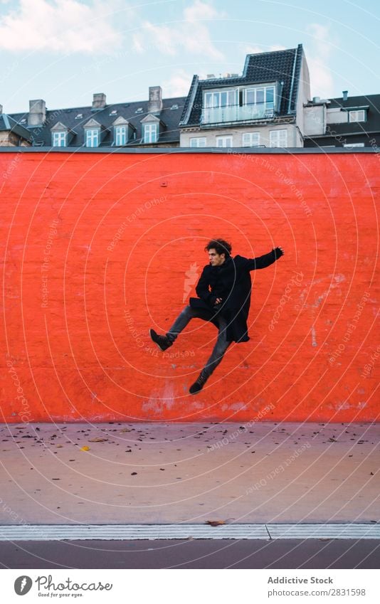 Mann springt an die orangefarbene Wand gutaussehend Großstadt Straße springen Orange Freude Trick Jugendliche Stadt Lifestyle lässig Mode Stil Erwachsene modern