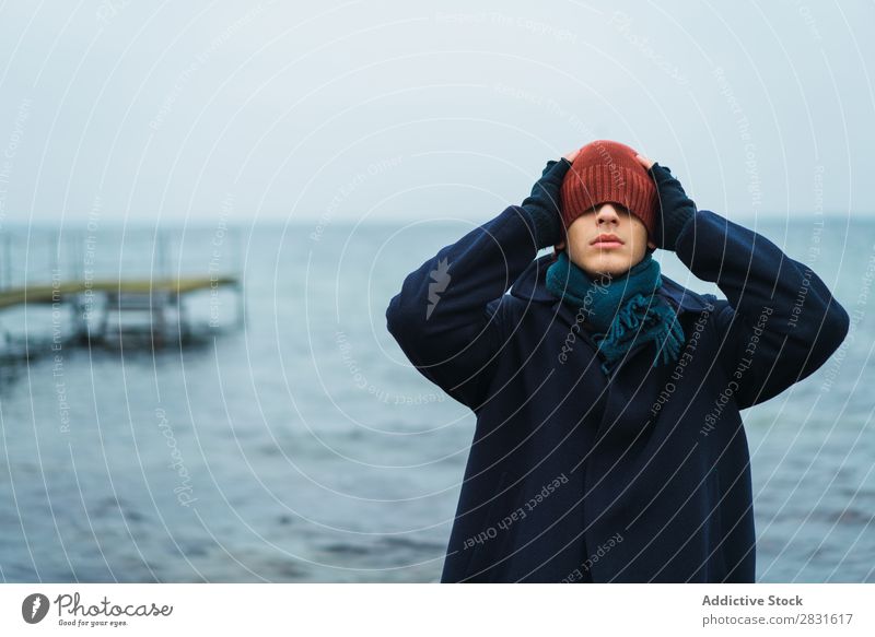 Mann setzt Hut auf Hut auf Augen Stil Seeküste kalt Mantel warme Kleidung anmachend ausrichten Meer Natur Jugendliche Erwachsene blau Ferien & Urlaub & Reisen
