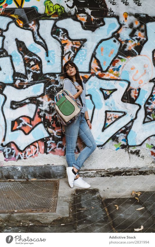 Selbstbewusste Frau, die auf der Straße posiert. Mensch lässig Körperhaltung selbstbewußt Stil Accessoire Rucksack reisend Graffiti Straßenbelag Stadt