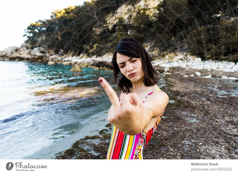 Ausdrucksstarkes Mädchen am Strand mit Mittelfinger Frau gestikulieren Provokation angriffslustig Sommer missbräuchlich Gefühle Jugendliche