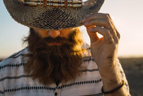 Bartiger Mann mit Hut gegen Sonnenlicht bärtig Cowboy Stil selbstbewußt Natur Porträt Länder maskulin ernst Strohhut Outfit Außenaufnahme Ausdruck Reisender