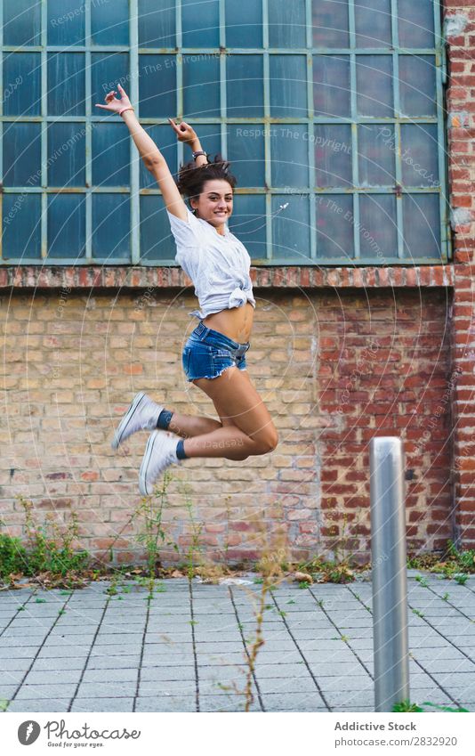 Frau, die auf die Straße springt. Körperhaltung Gleichgewicht akrobatisch feminin Lebensfreude gymnastisch Jugendliche Ausdruck Pose expressiv Leistung Aerobic