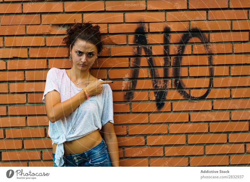 Frau, die auf ein Wort an der Wand zeigt. zeigen Straße verboten negativ Verleugnung Menschenleer Stadt Mitteilung Negation Ablehnung Grimasse gestikulieren