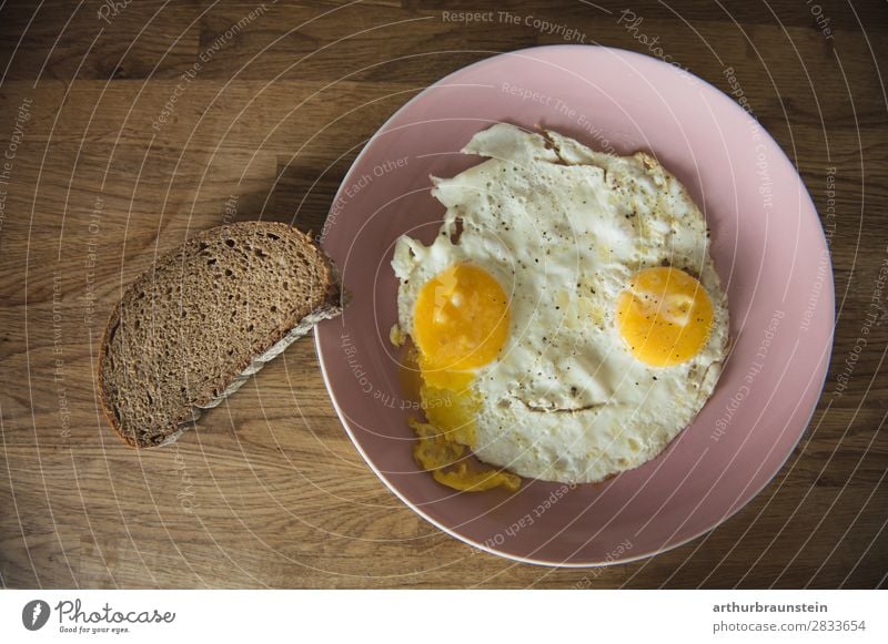 Spiegelei Gesicht mit Brotscheibe Lebensmittel Ei Ernährung Frühstück Geschirr Teller Gesundheit Gesunde Ernährung Koch Holz Essen authentisch braun gelb rosa