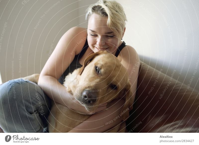 Junge Frau lächelt und hält blonden Labrador im Arm Stil Freude schön harmonisch Wohlgefühl Wohnung Jugendliche 18-30 Jahre Erwachsene Jeanshose kurzhaarig