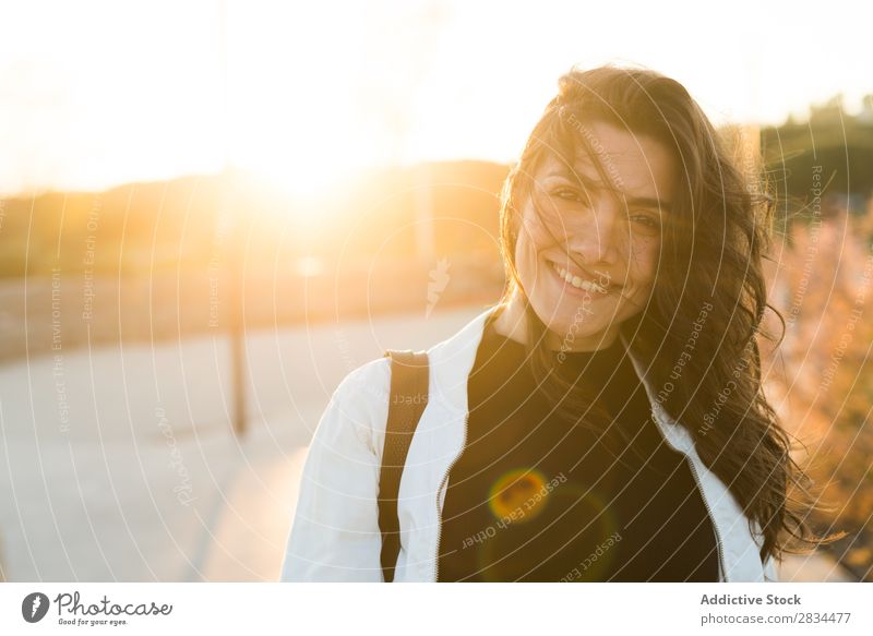 Lächelnde bezaubernde Frau im Sonnenlicht Körperhaltung Schickimicki Porträt Stil genießen wehendes Haar Stadt heiter brünett selbstbewußt lachen Jugendliche
