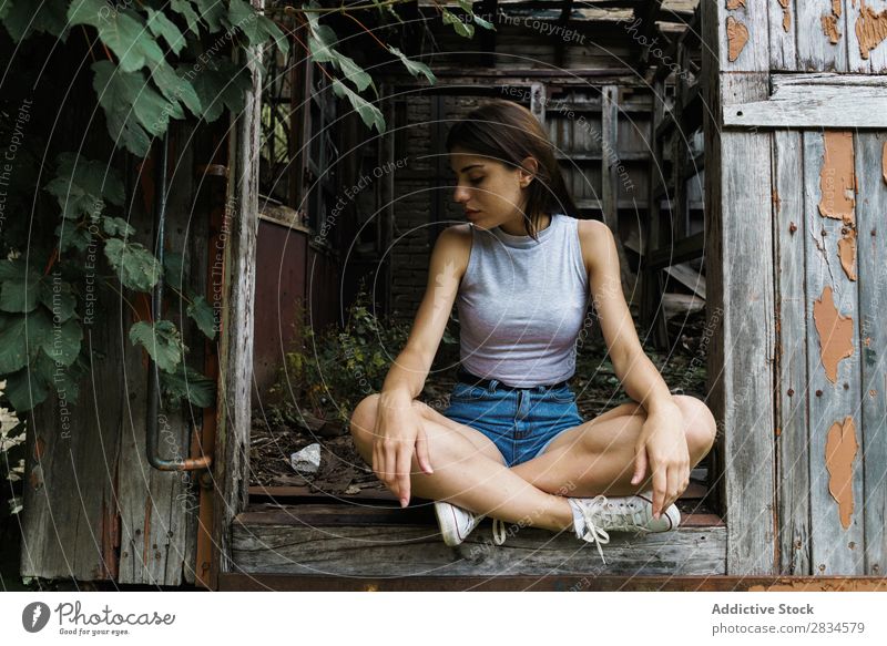 Frau, die in einer verfallenen Kabine posiert. Körperhaltung Grunge zerstört Verlassen Sommer Gebäude erkunden romantisch sitzen verwittert selbstbewußt