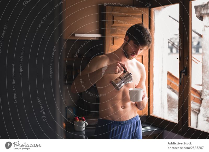 Mann, der einen Kaffee in die Tasse gießt. Gießen Morgen Füllung Fürsorge besinnlich Becher heiß trinken Denken Frühstück Lifestyle heimwärts Porträt Küche