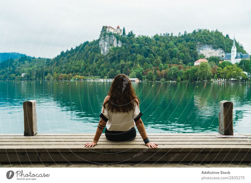 Frau, die auf die Hügel am See schaut. sitzen Anlegestelle Berge u. Gebirge Küste Aussicht Natur Wasser Landschaft Sommer blau grün schön Szene
