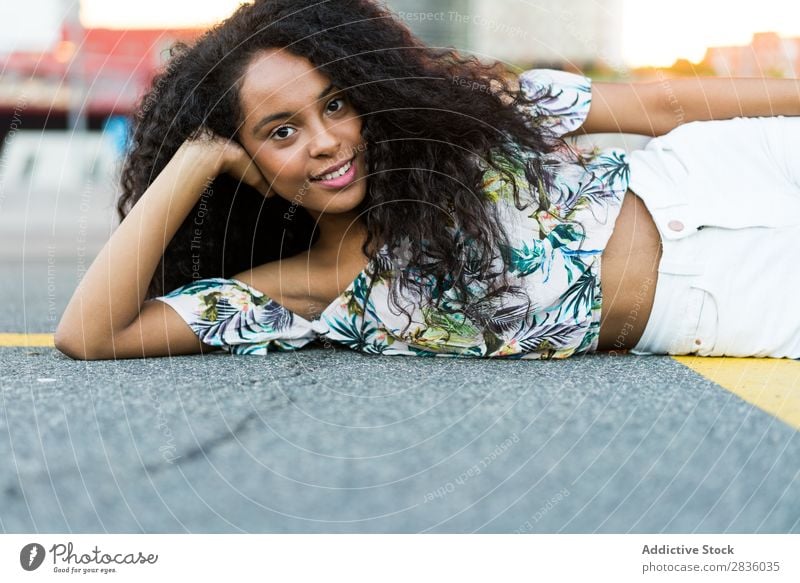 Frau auf der Straße liegend hübsch Jugendliche Porträt lügen Straßenbelag Asphalt Blick in die Kamera schwarz Afrikanisch Großstadt Stadt Kopf schön lockig