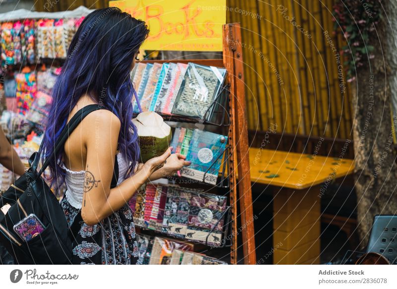 Hübsche Frau, die sich ein Notizbuch aussucht. hübsch Straße Jugendliche schön Kommissionierung auserwählend Porträt Kokosnuss trinken Trinkhalm Behaarung