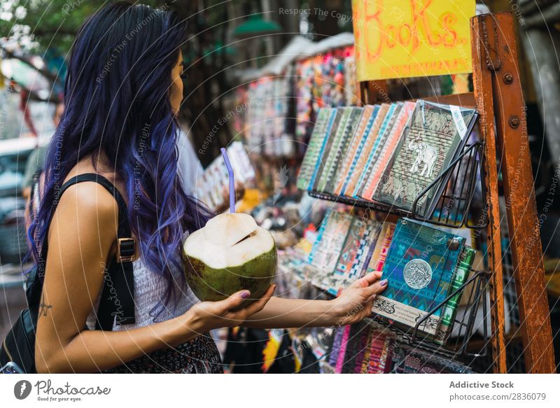 Hübsche Frau, die sich ein Notizbuch aussucht. hübsch Straße Jugendliche schön Kommissionierung auserwählend Porträt Kokosnuss trinken Trinkhalm Behaarung