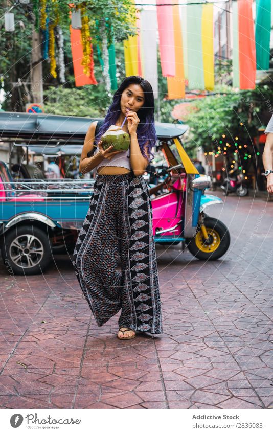 Junge Frau mit Kokosnussgetränk auf der Straße hübsch Jugendliche schön Porträt stehen trinken Trinkhalm Behaarung purpur asiatisch Östlich Mode attraktiv
