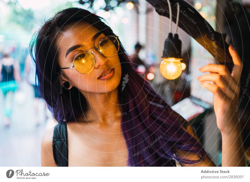Hübsche asiatische Frau beobachtet Lampe hübsch Straße Jugendliche schön Porträt berühren Knolle Baum Beleuchtung Behaarung purpur Östlich Mode attraktiv