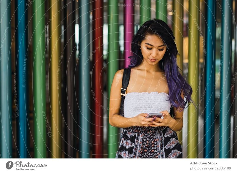 Junge Frau, die sich auf bunte Säulen stützt. hübsch Straße Jugendliche schön anlehnen mehrfarbig Porträt Behaarung purpur asiatisch Östlich Mode attraktiv