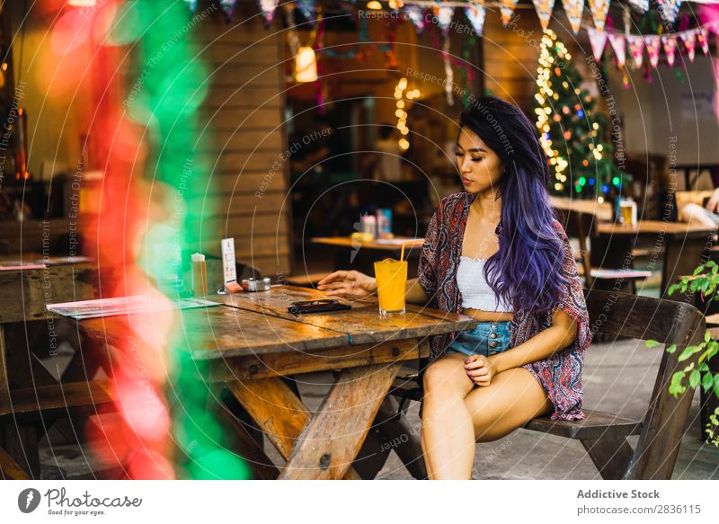 Frau mit Smartphone im Café hübsch Jugendliche schön Porträt Saft trinken PDA benutzend Browsen Behaarung purpur asiatisch Östlich Mode attraktiv Großstadt