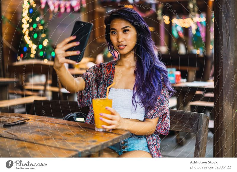 Frau mit Smartphone im Café hübsch Jugendliche schön Porträt Saft trinken PDA benutzend Browsen Behaarung purpur asiatisch Östlich Mode attraktiv Großstadt