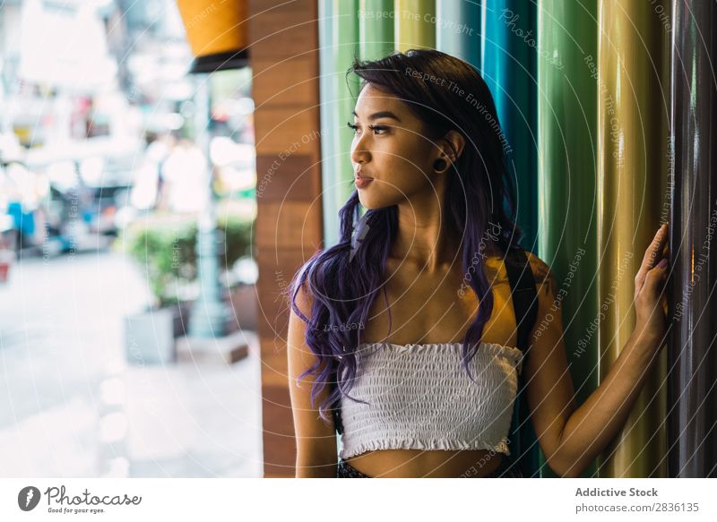 Junge Frau, die sich auf bunte Säulen stützt. hübsch Straße Jugendliche schön anlehnen mehrfarbig Porträt Behaarung purpur asiatisch Östlich Mode attraktiv