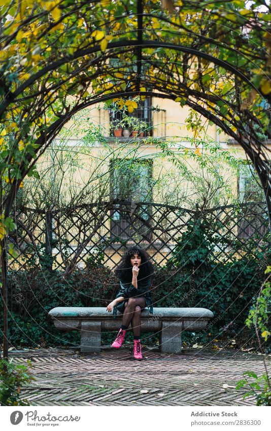 Frau auf dem Zaun im Park attraktiv Großstadt modisch lockig brünett Jacke Mode Jugendliche schön hübsch Straße Model Stil Behaarung Beautyfotografie Dame