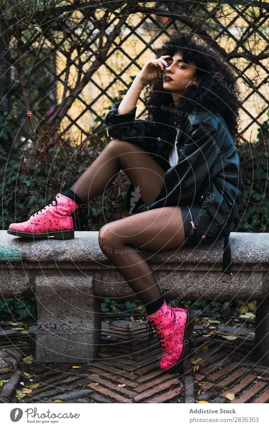 Frau auf dem Zaun im Park attraktiv Großstadt modisch lockig Haltehaar brünett Jacke Mode Jugendliche schön hübsch Straße Model Stil Behaarung Beautyfotografie