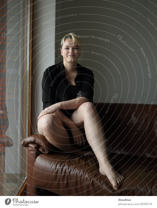 Junge Frau mit langen Beinen sitzt barfuß sitzt auf der Couch Stil Freude schön Leben Wohlgefühl Wohnung Raum Jugendliche 18-30 Jahre Erwachsene Barfuß blond