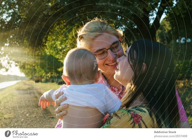 Glückliches lesbisches Paar mit Kind Mutter Park grün Sonnenstrahlen Mensch Frau Fröhlichkeit Sommer Lifestyle Liebe gleichgeschlechtliche Eltern Homosexualität