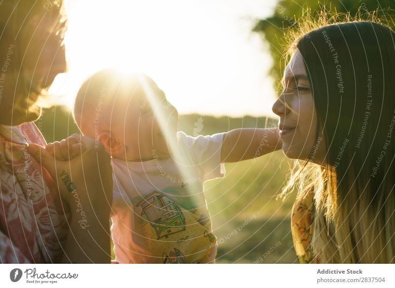 Glückliche Familie mit Kind Mutter Park grün tragen Sonnenstrahlen Mensch Frau Fröhlichkeit Sommer Lifestyle Liebe gleichgeschlechtliche Eltern Homosexualität