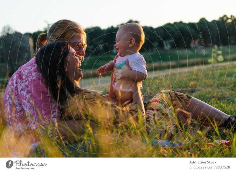 Glückliche lesbische Familie mit Kind Mutter Park Rasen grün Sonnenstrahlen Mensch Frau Fröhlichkeit Sommer Lifestyle Liebe gleichgeschlechtliche Eltern