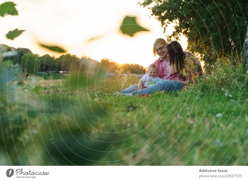 Lesbische Familie mit Kind auf dem Rasen Mutter Park grün Sonnenstrahlen Glück Mensch Frau Fröhlichkeit Sommer Lifestyle Liebe gleichgeschlechtliche Eltern