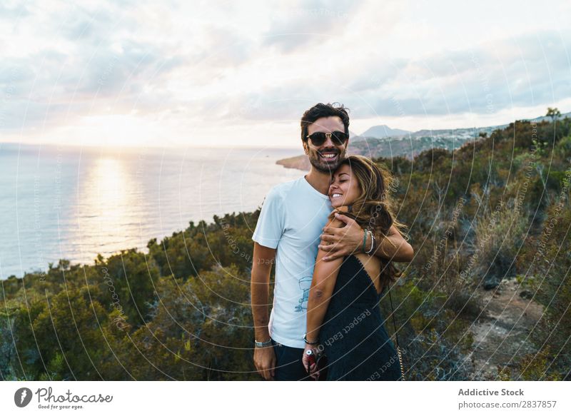 Fröhliches Paar, das auf der Natur posiert. Landschaft Körperhaltung Meer umarmend Tourist Abenteuer Panorama (Bildformat) Freiheit Erholung Zusammensein