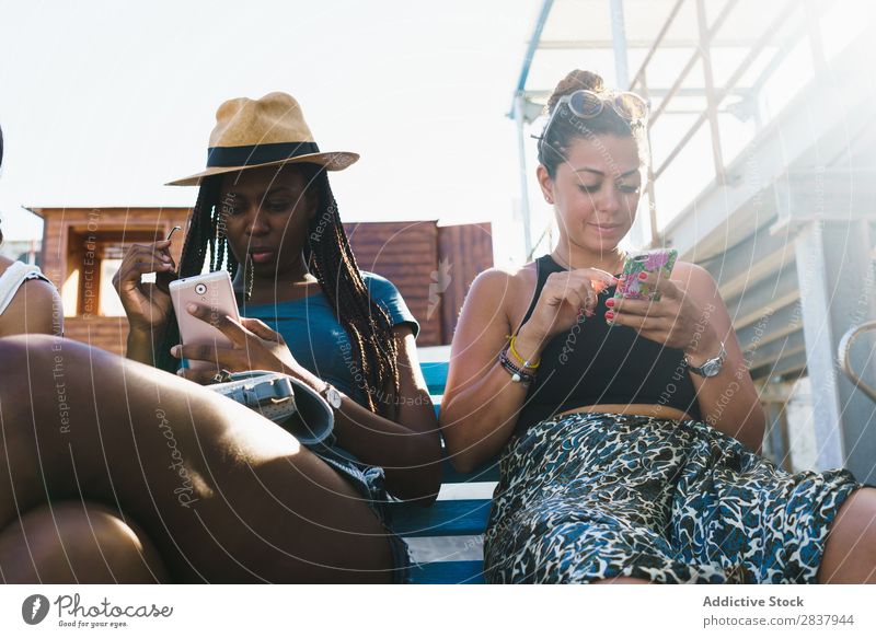 Freunde mit Smartphones entspannen sich draußen. Mensch Freundschaft Erholung PDA Mitbenutzung reisend Terrasse heiter Technik & Technologie Fröhlichkeit