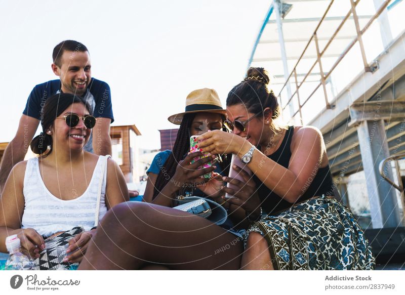 Freunde mit Smartphones entspannen sich draußen. Mensch Freundschaft Erholung PDA Mitbenutzung reisend Terrasse heiter Technik & Technologie Fröhlichkeit