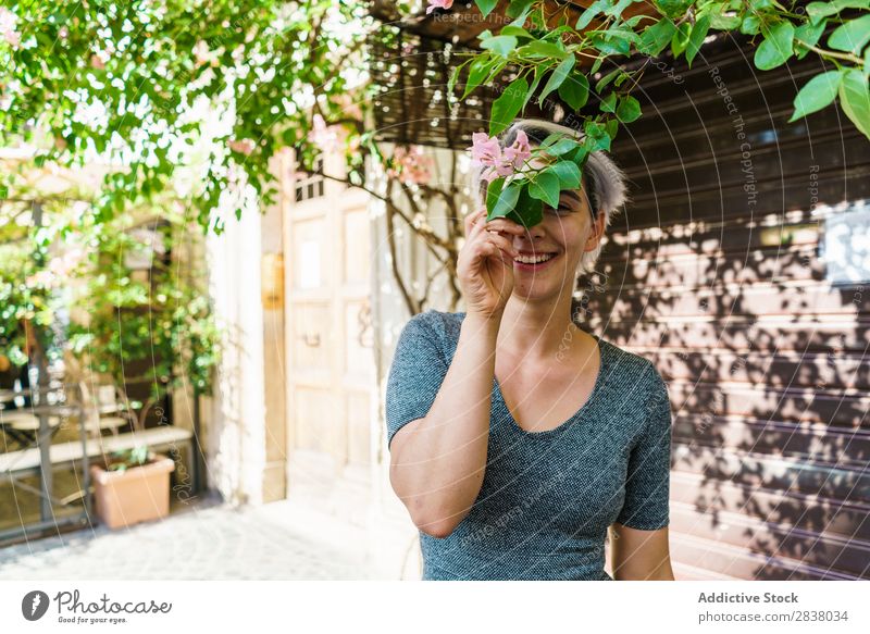 Frau bedeckt Gesicht mit Blume Straße Baum Überstrahlung Körperhaltung Deckfläche Freude heiter Sommer Frühling Großstadt attraktiv Mädchen schön Behaarung