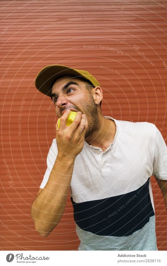 Mann isst Apfel an der Wand Essen Wut so tun, als ob Spaß haben Appetit & Hunger expressiv verrückt Körperhaltung Gesichtsbehandlung Verstand spielerisch