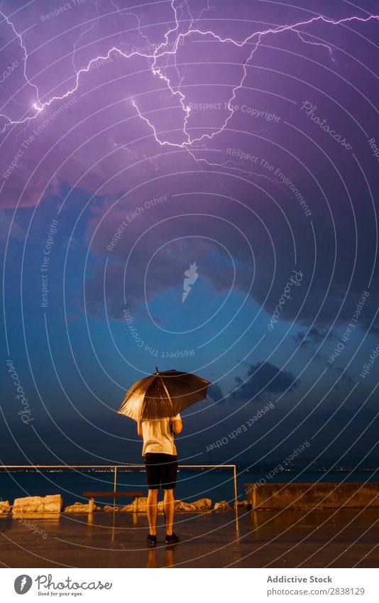 Mann mit Regenschirm unter stürmischem Himmel Donnern Unwetter Stauanlage Wetter Victoria & Albert Waterfront Gewitter Blitze natürlich reisend vertikal
