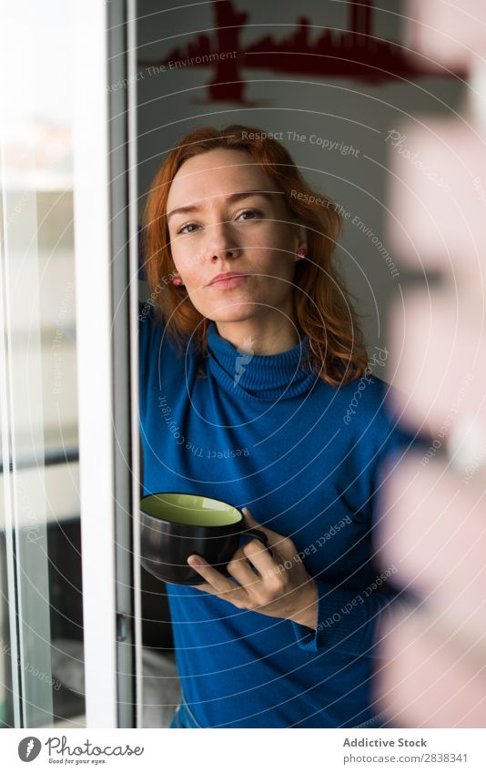 Frau mit Tasse am Fenster Becher trinken Getränk heiß Blick in die Kamera hübsch Fürsorge stehen schön rothaarig Jugendliche attraktiv Mensch Mädchen Porträt