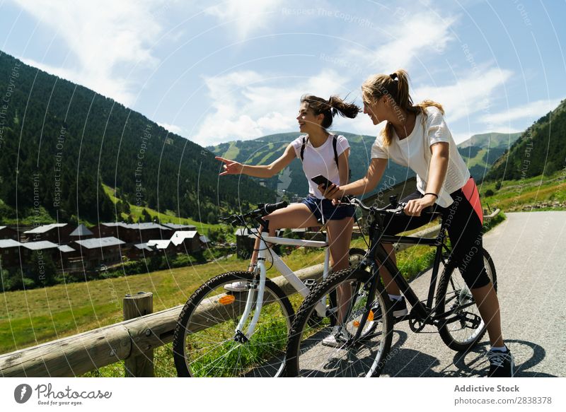 Frauen, die Smartphones auf Fahrrädern benutzen. Fahrrad PDA benutzend Freundschaft sportlich Sport Zyklus Mädchen Aktion Lifestyle Fahrradfahren Mensch