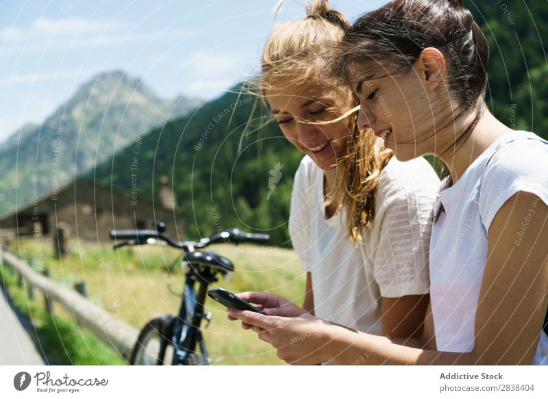 Frauen mit Fahrrädern beim Surfen im Smartphone sitzen Zaun PDA Browsen sportlich Fahrrad Freundschaft Sport Zyklus Mädchen Aktion Lifestyle Fahrradfahren