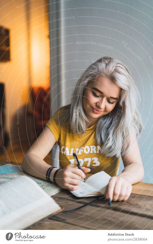 Hübsche Frau beim Schreiben am Tisch hübsch heimwärts Jugendliche blond sitzen Buch Landkarte Wege & Pfade schön schreibend Lächeln Lifestyle Beautyfotografie
