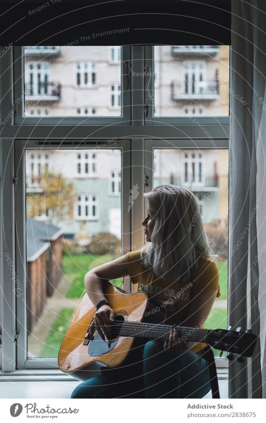Musikant am Fenster sitzend Frau hübsch heimwärts Jugendliche Musiker Gitarre Inspiration Spielen blond schön Lifestyle Beautyfotografie attraktiv Porträt Dame