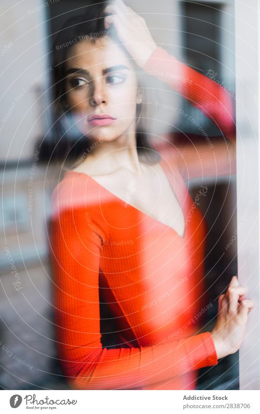Hübsche Frau, die sich an das Fenster lehnt. heimwärts hübsch anlehnen Orange Kleid Jugendliche Körperhaltung Erholung Porträt schön Lifestyle Beautyfotografie