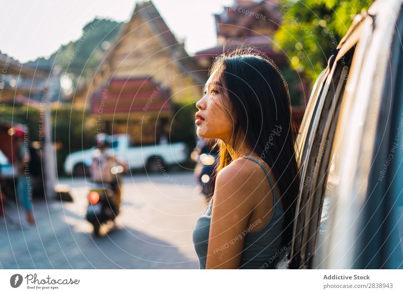 Asiatin, die sich auf das Auto stützt. Jugendliche Lifestyle schön Mädchen Fröhlichkeit Kaukasier Ferien & Urlaub & Reisen Erwachsene Fahrzeug PKW Frau frei